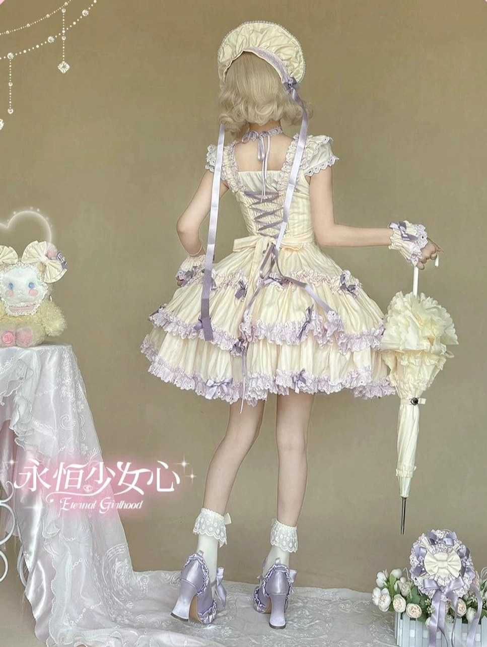Back full-body studio view of cream yellow and purple striped Lolita JSK with lace-up back closure, matching bonnet, and layered ruffled purple-trimmed skirt