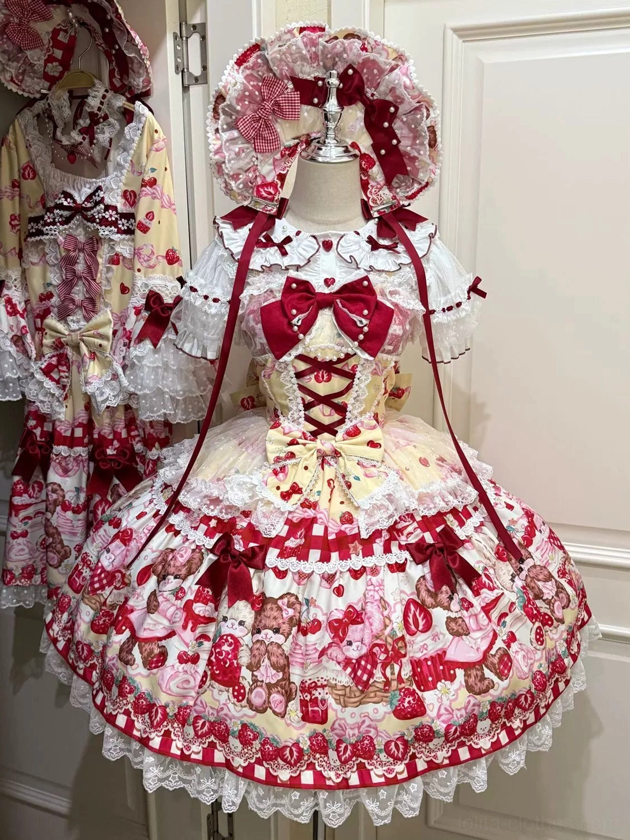 Cream yellow strawberry bear print sweet lolita JSK dress front view with red bow and layered ruffled lace hem