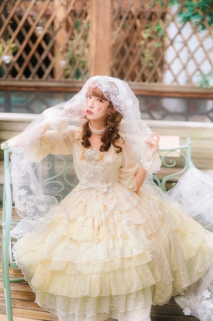 Cream yellow Sweet Lolita OP dress with classic sweetheart neckline, tiered lace ruffle skirt, and pearl choker, wedding veil outdoor terrace view