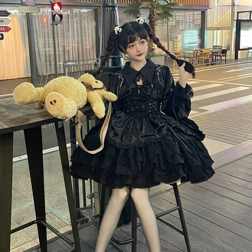 Black Cross Medal Gothic Lolita dress with bolero and puff sleeves styled outdoors with crossbody leather bag and teddy bear prop, front-three-quarter outdoor coordinate view