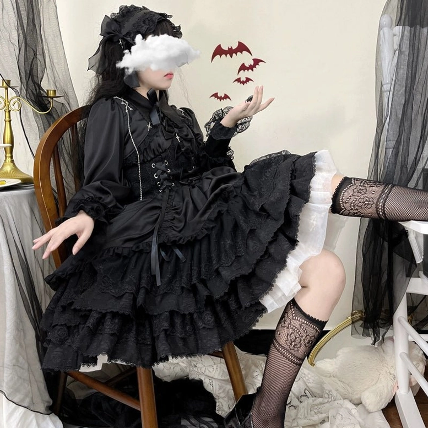 Low-angle view of Black Cross Medal Gothic Lolita dress showing drawstring lift-up hem feature, black fishnet stockings, gothic headdress, white skirt lining detail, and ruffled lace layers