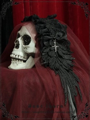 Custom color gothic lolita headband with blue velvet ribbon bow on black lace base, displayed on skull prop with burgundy velvet backdrop, silver cross and wing embroidery