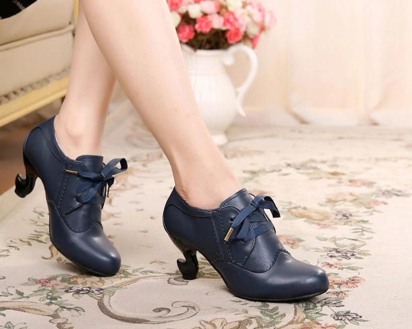 Cyan blue Sweet Lolita Mary Jane high heel shoes with curved spool heel, metal-tipped ribbon lace fasteners, and scalloped edge trim, worn on indoor background