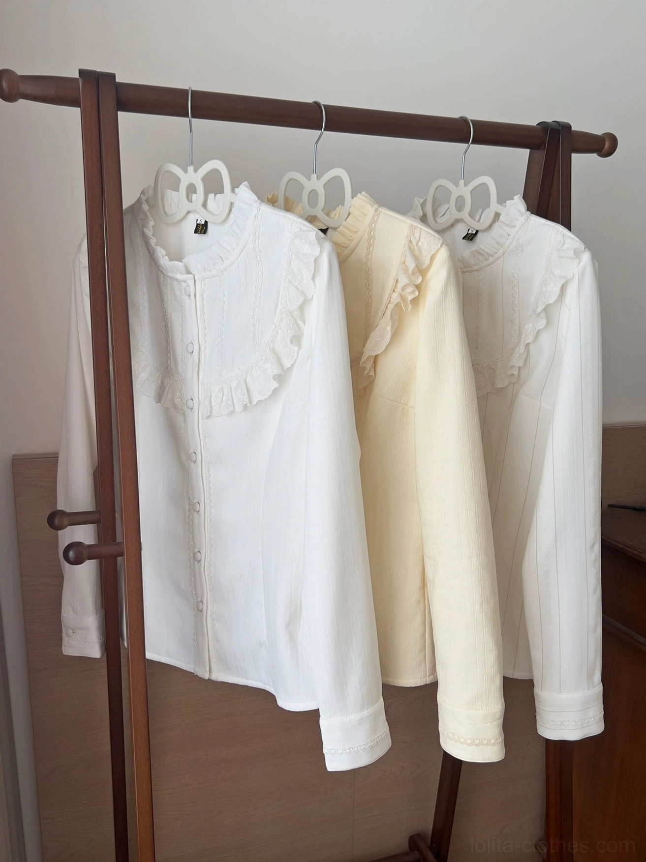 Multiple basic daily lolita fleece blouses in white and cream yellow colors displayed on clothing rack showing unified ruffled stand collar design