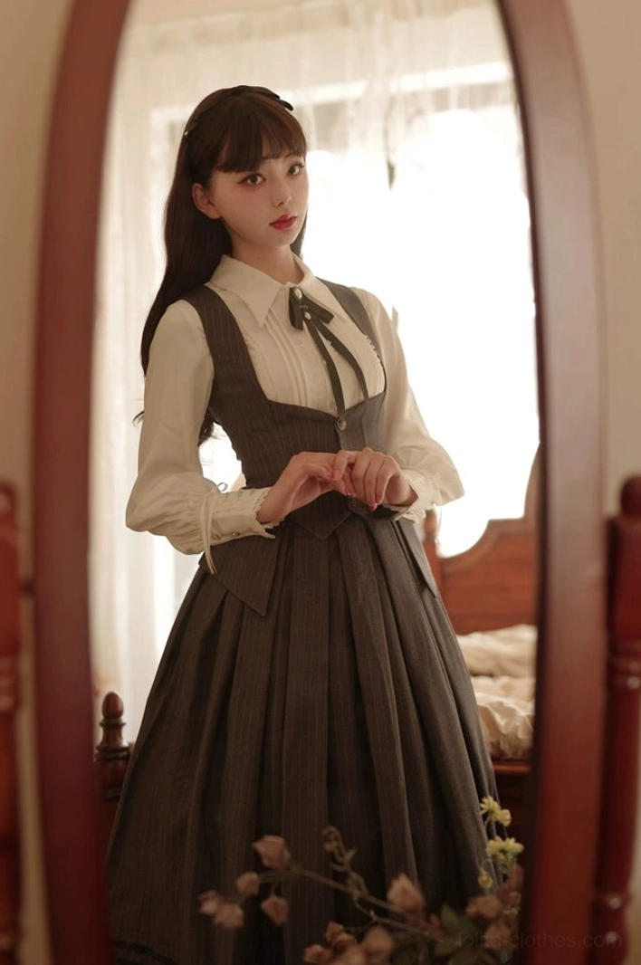 Daily Lolita coordinate with white pointed collar blouse, high-waisted solid brown suspender skirt, matching grey bow tie, full-body mirror reflection in vintage bedroom studio setting