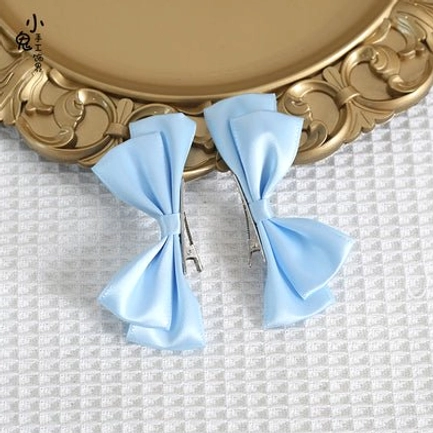 Dark navy blue Sweet Lolita bow hair clips flat lay display on decorative golden tray and checkered fabric showing deep navy satin material and neat bow silhouette