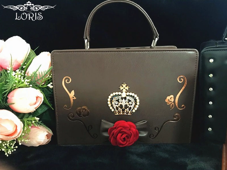 dark brown gothic lolita crown handbag flat lay front view metallic crown red fabric rose black bow golden swirling patterns dark backdrop pink artificial flowers