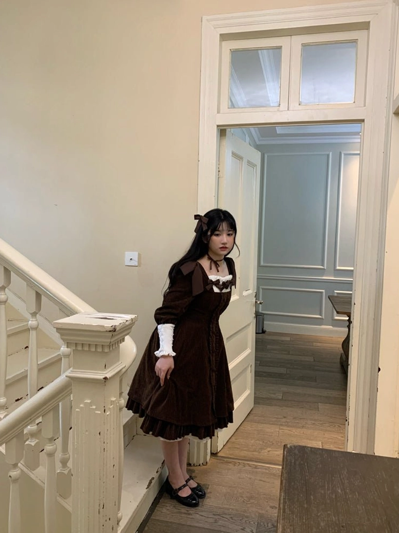 Dark brown velvet Lolita OP dress mirror full-body shot in vintage European hallway, featuring square neckline with ruffled trim, contrast white cuffs, and simple fitted waist silhouette