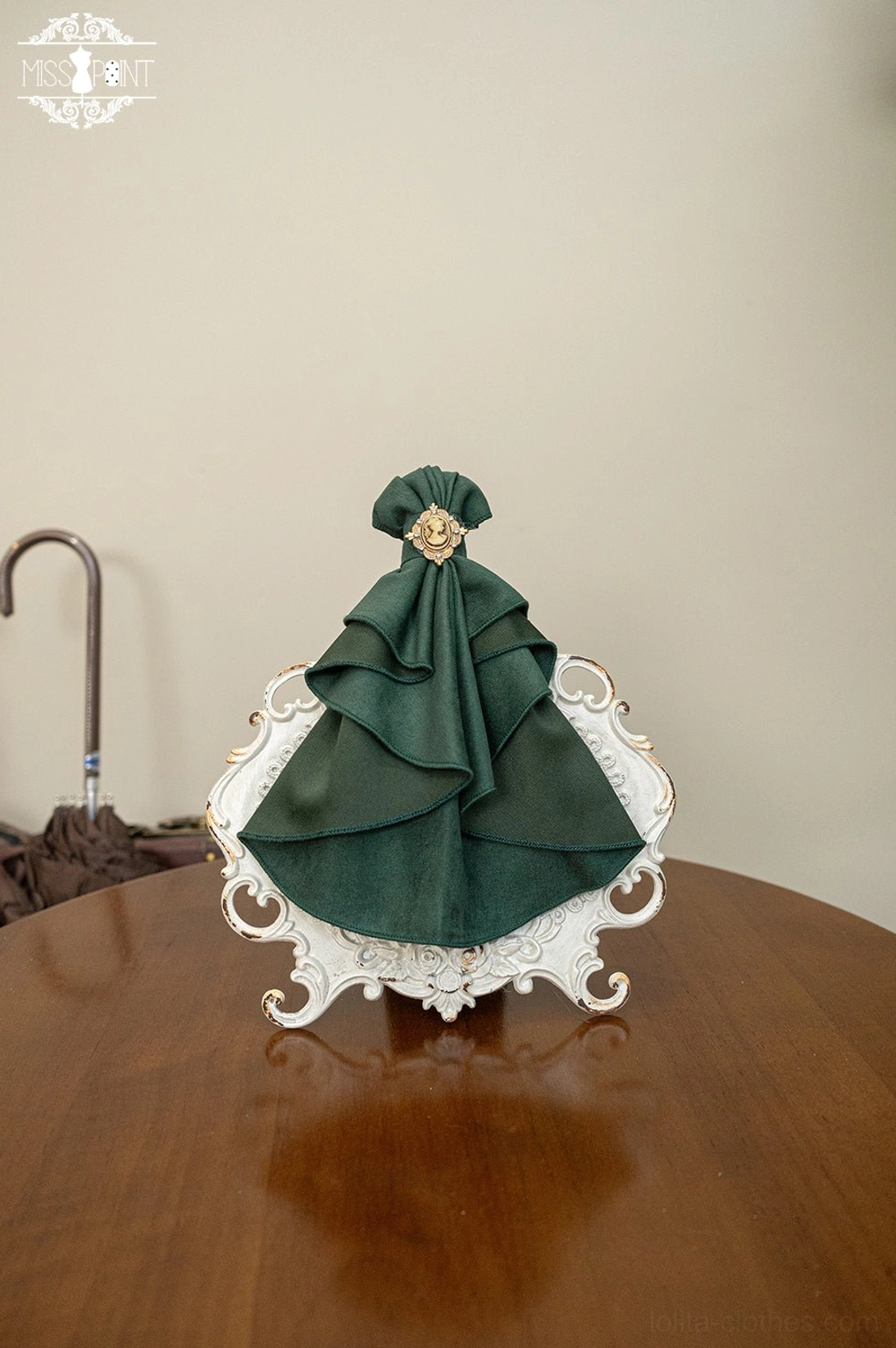 Dark green emerald lolita bow tie brooch accessory satin ruffled bow gold round brooch flat lay vintage tray product photography