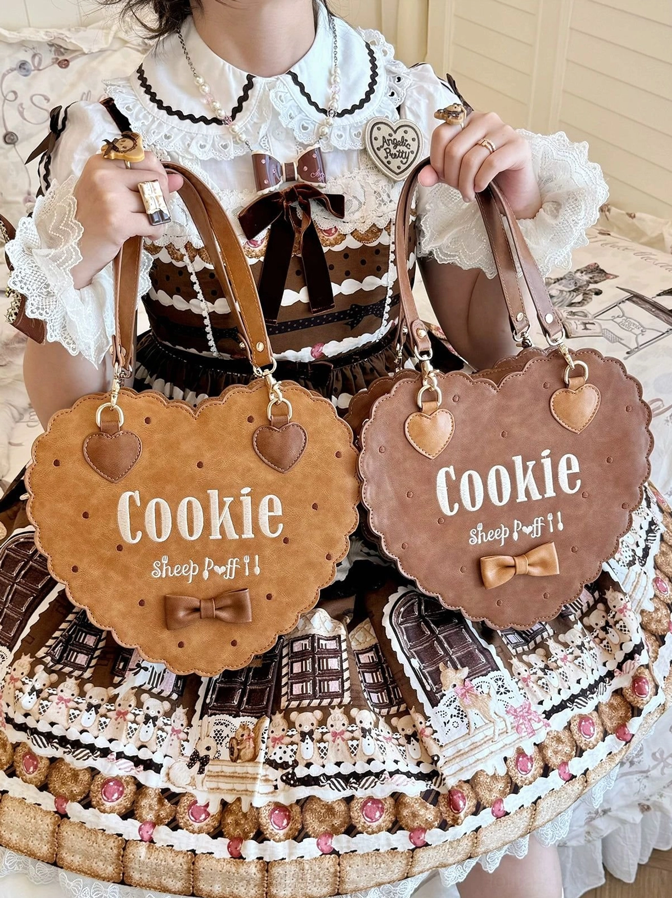 Close-up of deep brown scalloped heart-shaped cookie lolita handbag with embroidered lettering tiny bow and heart charm details held by model in lolita outfit