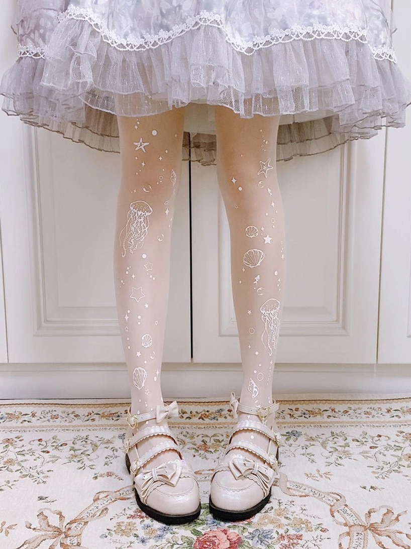 Close-up detail view of Deep Sea Jellyfish 20D white Lolita tights showing intricate printed jellyfish starfish and shell patterns on sheer velvet fabric with light gray lace-trimmed Lolita skirt