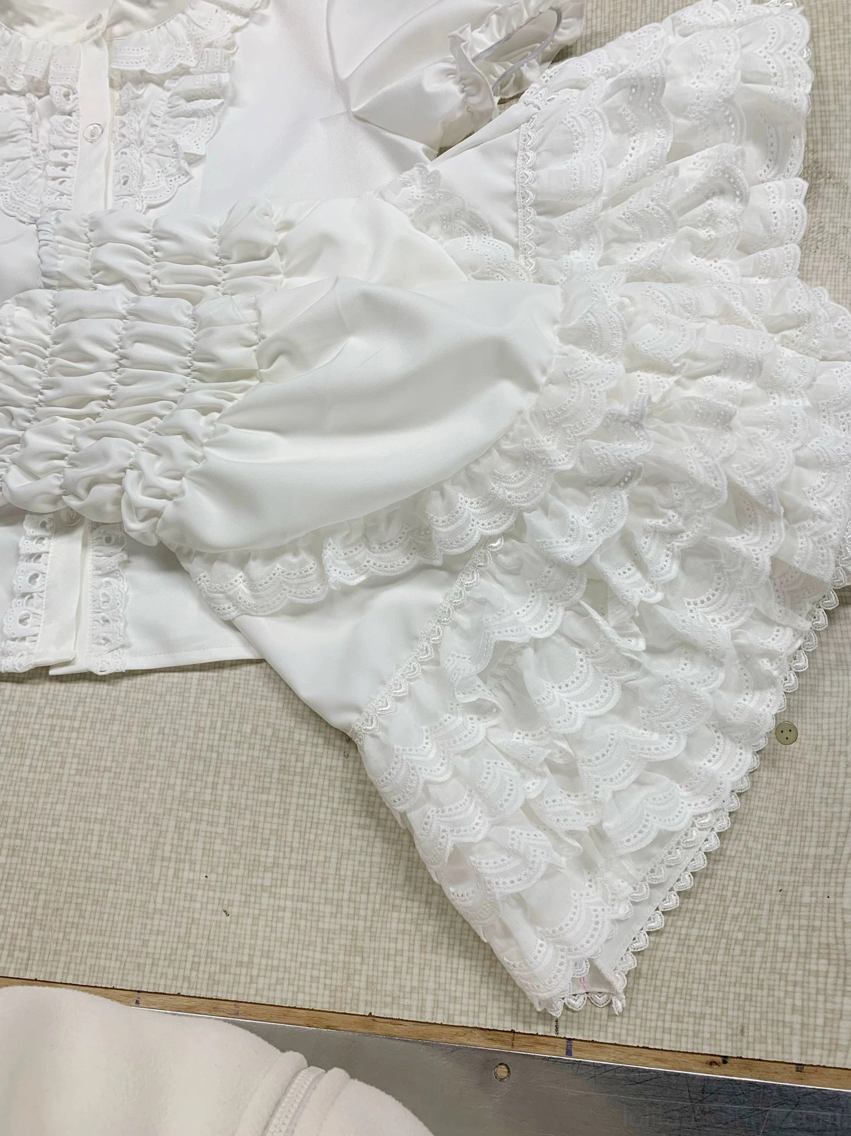 Detachable lolita princess sleeves with embroidered eyelet lace ruffles, shirred elastic cuffs and layered ruffle edges in pure white cotton fabric, close-up flat lay detail shot
