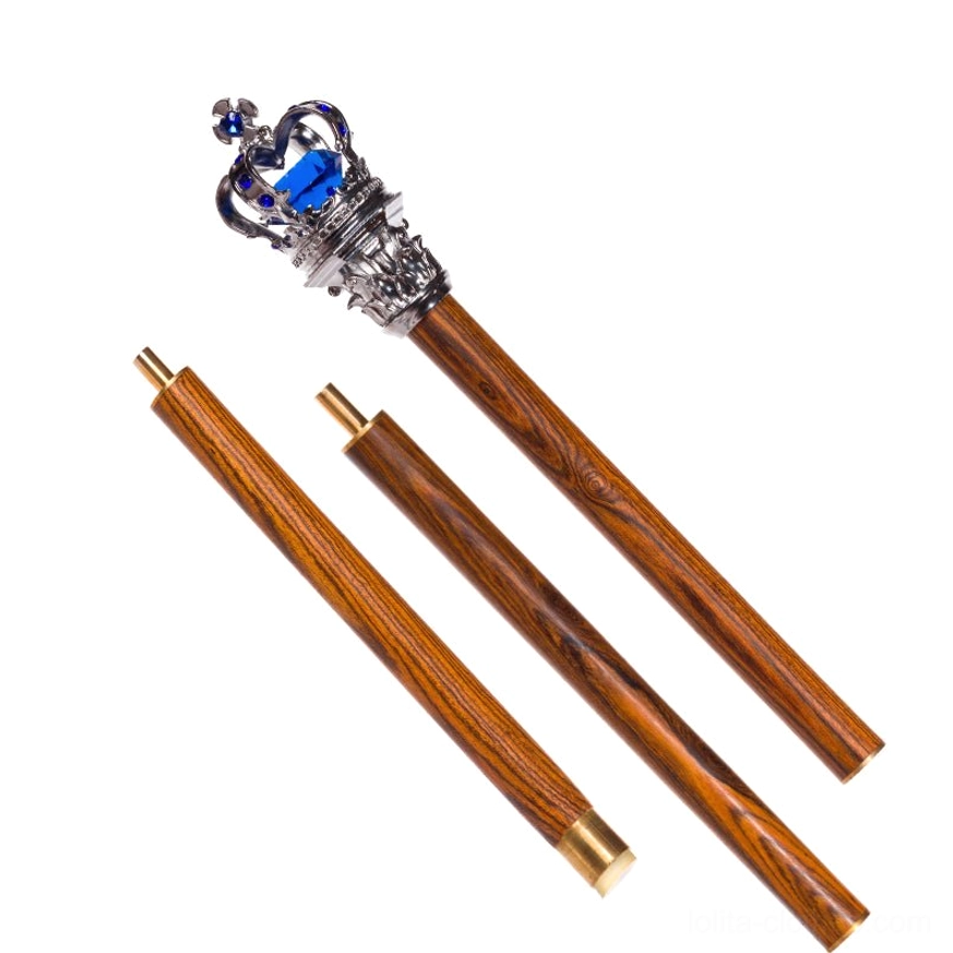 Detachable royal lolita scepter flat lay with blue gemstone crown top, matte black wood-grain pole, three assembly sections, studio background