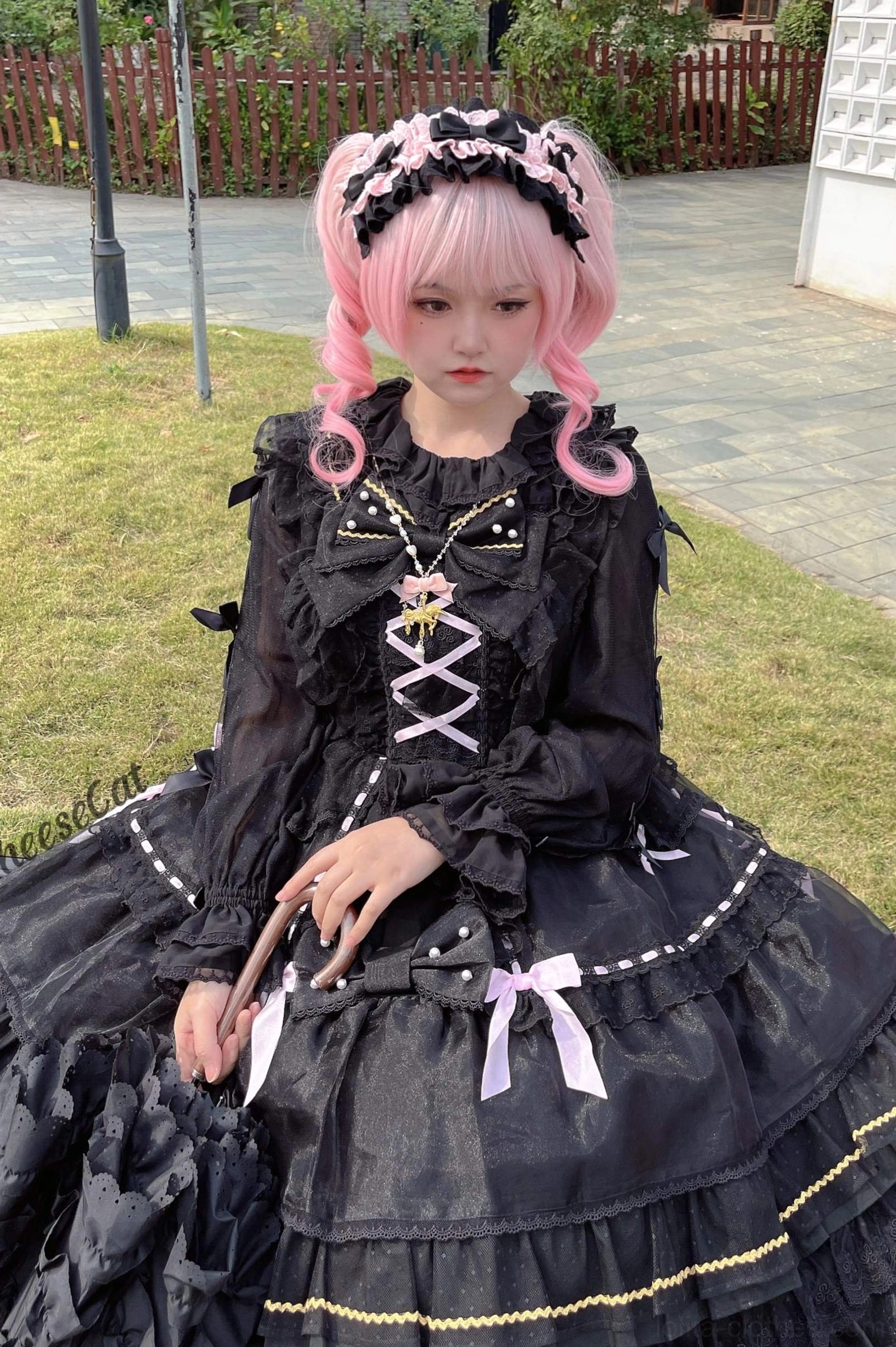 Black cotton lolita headdress with matching headdress paired with black OP dress featuring cross lace-up front on pink wig model at indoor wooden table setting with pearl handbag accessory