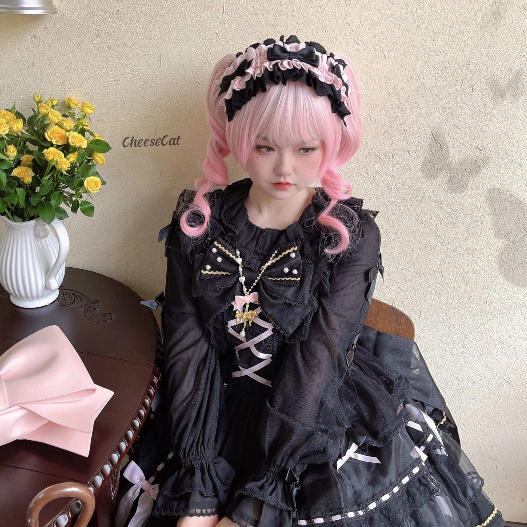 Black cotton lolita headdress with black lace trim paired with black OP dress featuring cross lace-up bodice and sheer ruffled sleeves on pink wig model at cafe-style indoor backdrop