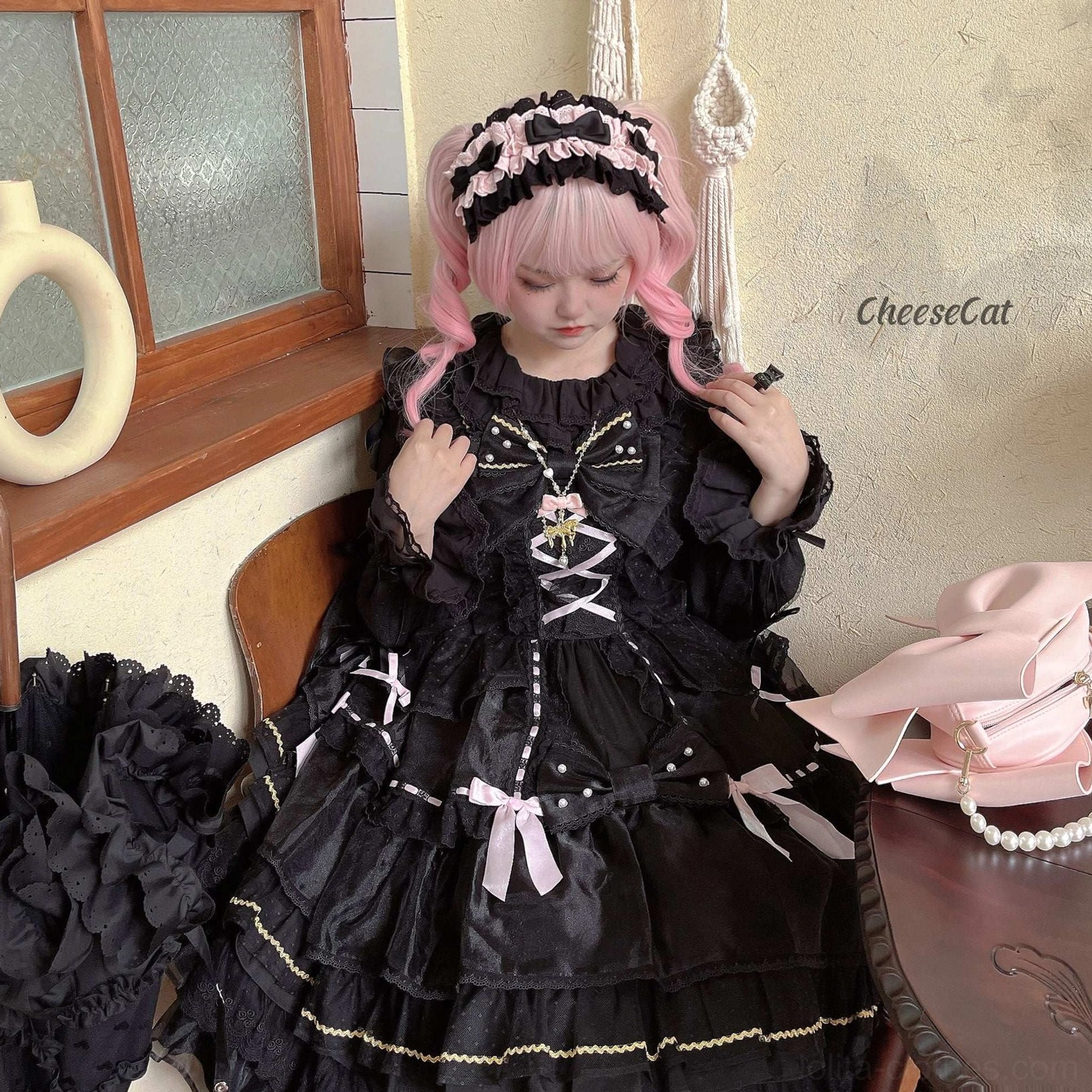 Black lace cotton lolita headdress with white satin trim and layered bow accents on pink wig model at indoor flower vase table backdrop showing ruffled lace details and delicate construction