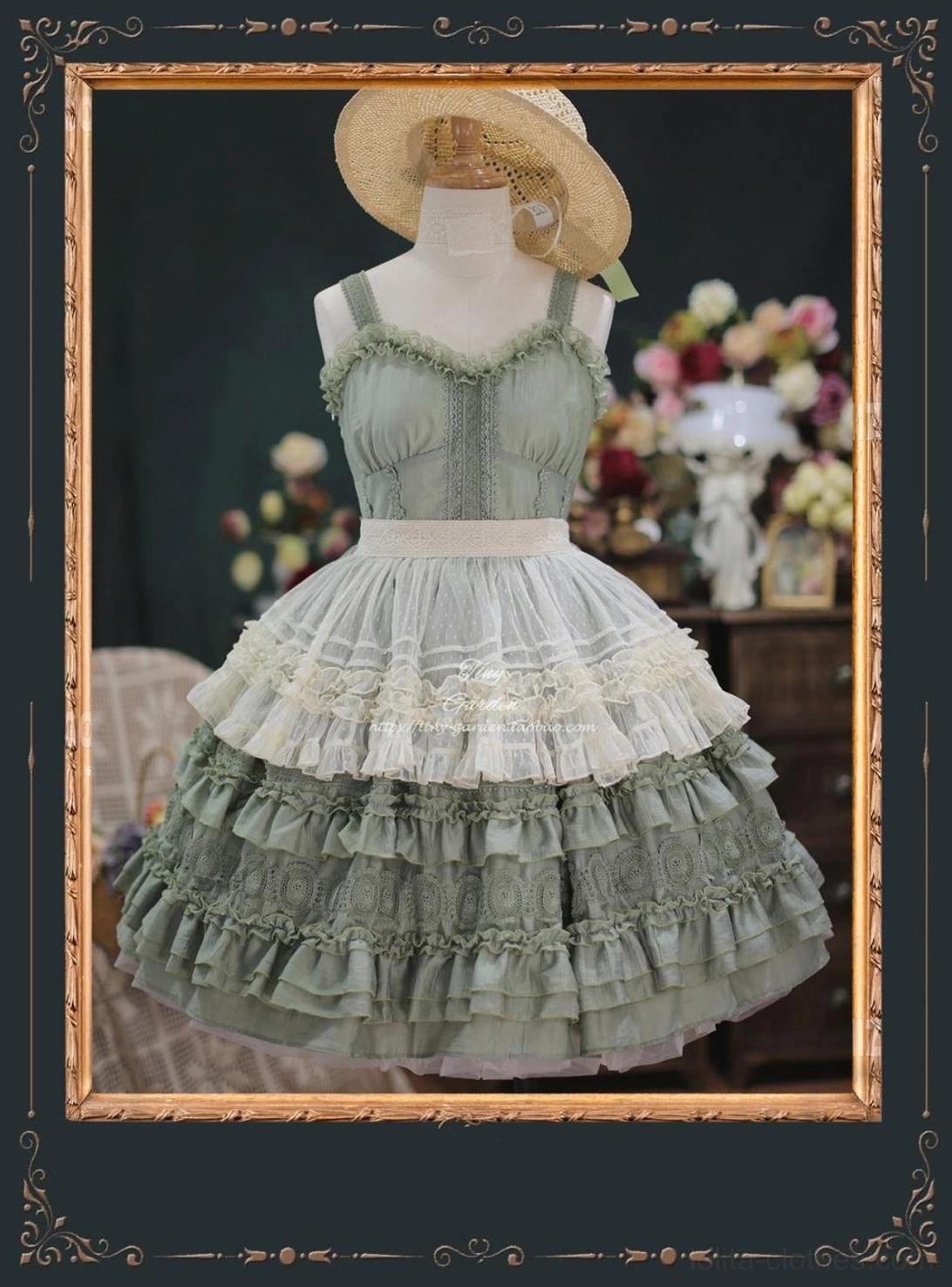 Grayish green lolita JSK with detachable lace apron overlay creating two-piece layered silhouette, mannequin wears straw boater hat, ruffled skirt trims visible against vintage floral background