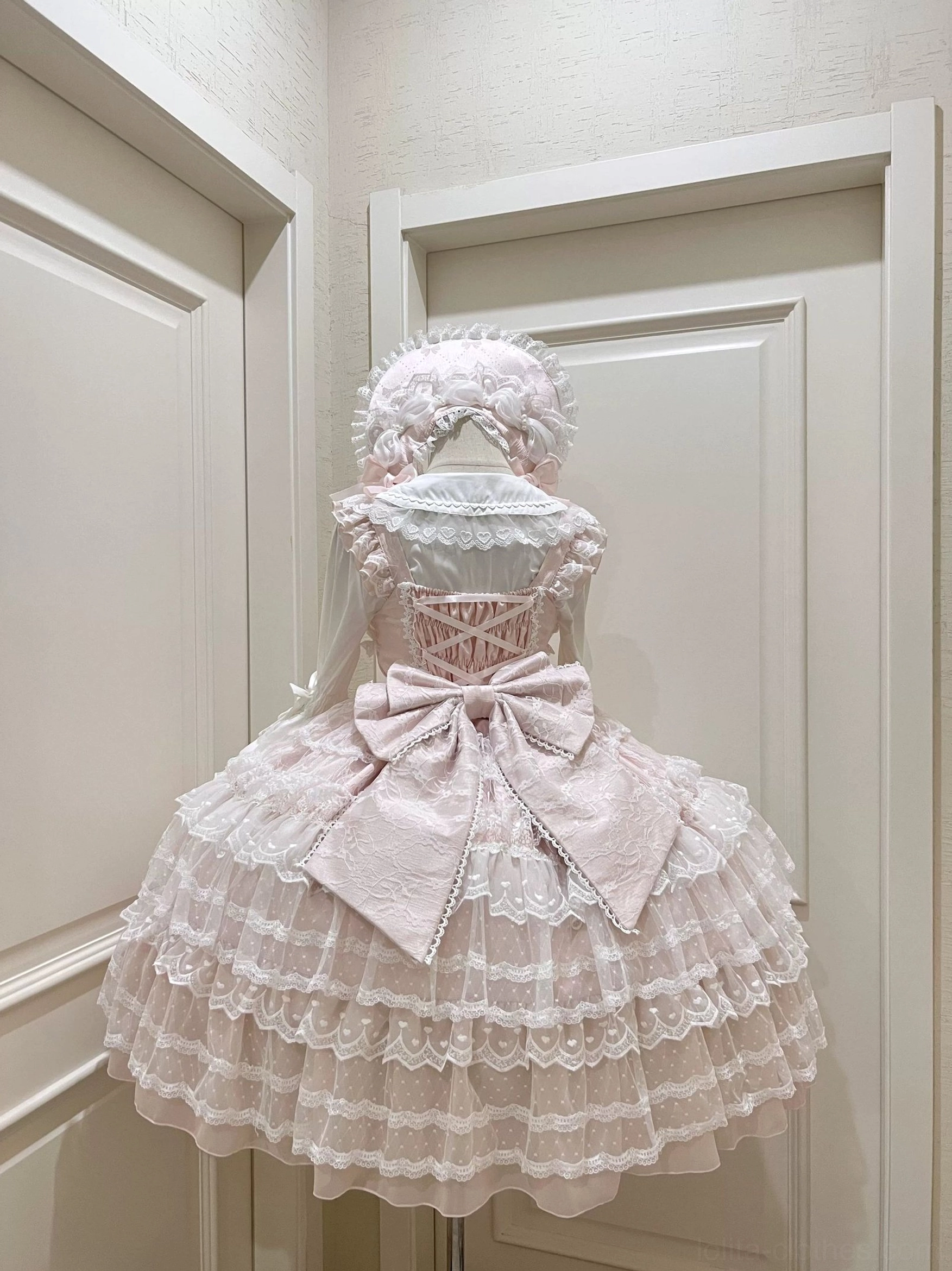 Light pink Lolita JSK dress suit with corset-style lace bodice tiered skirt and large waist satin bow back view display