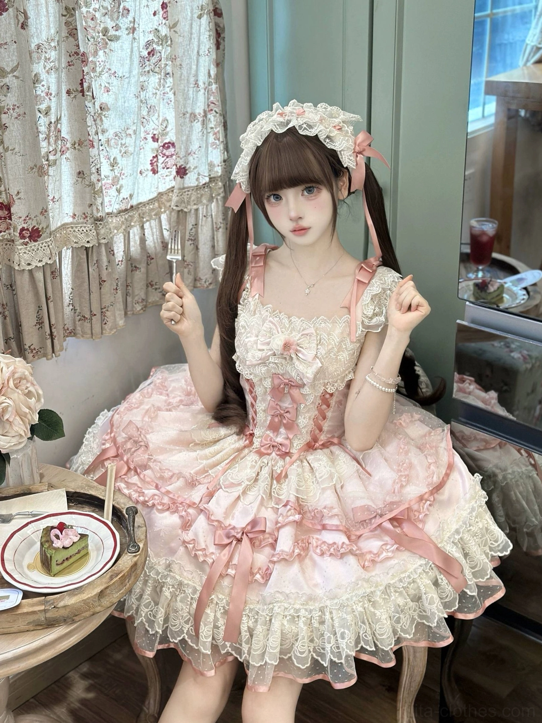 Pink sweet lolita jumper skirt front eye-level shot indoor vintage curtained tea studio, ruffled lace bodice and skirt, pink ribbon hair accents, twin-tailed model with raised hands pose