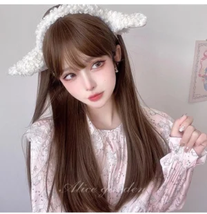 Elegant long straight lolita wig with air bangs in chestnut brown worn with fluffy sheep ear headband and pink floral ruffled blouse on female model in pastel bedroom setting