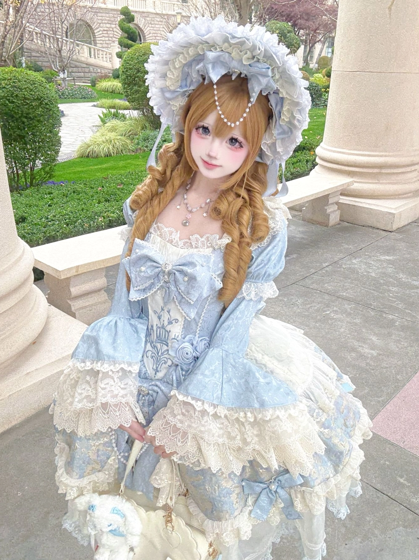 Elegant sweet Lolita dress half-body three-quarter view blonde twin-tails girl outdoor European building courtyard torso satin sash ruffled lace skirt hem