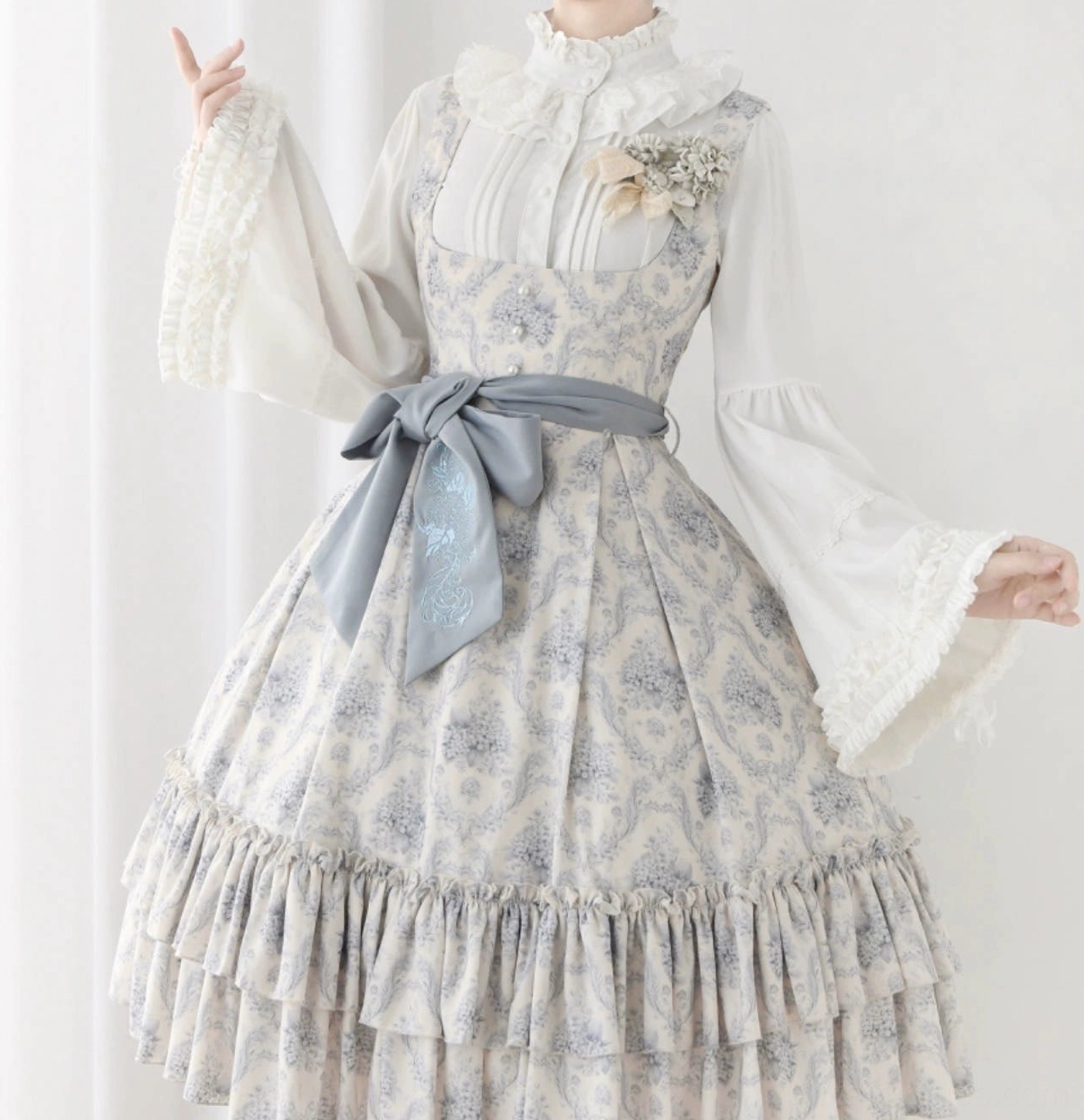 Classic Lolita blouse in milky white paired with comic-print jumperskirt and dark blue bow, three-quarter display showing ruffled cuff details and coordinated romantic aesthetic