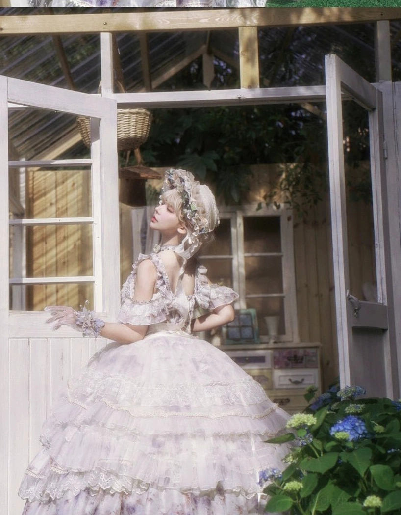 Back three-quarter full-length view of floral lolita jsk dress with adjustable back straps and chiffon fabric all-over floral print creating dramatic tiered ruffled ball gown effect