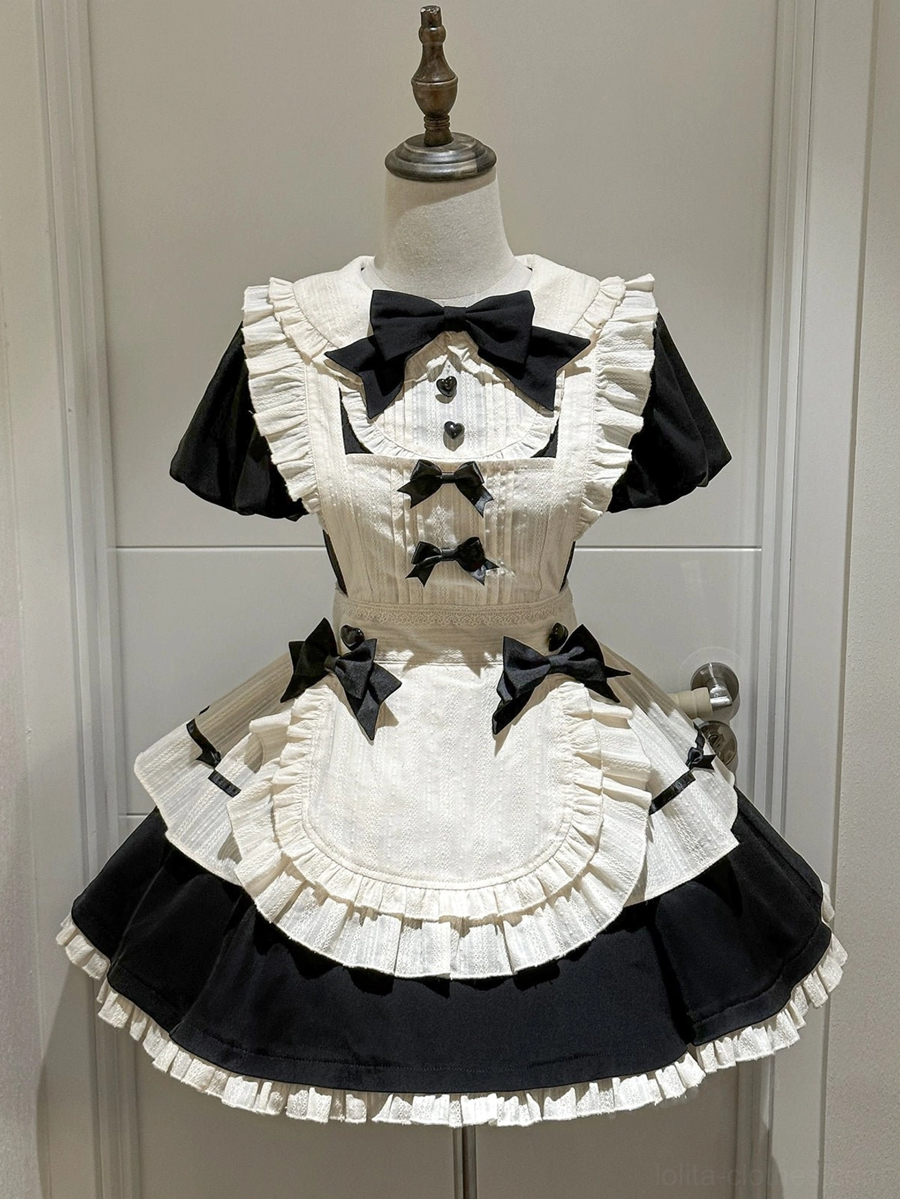 Black and cream enchanted maidette lolita OP dress front flat view on mannequin showing puffy sleeves peter pan collar and ruffled apron with decorative bows