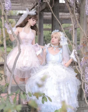 Endless Summer bridal lolita jsk dresses in pink and light blue worn by two models outdoors under wisteria pergola with tiered tulle ruffle skirts and bridal accessories