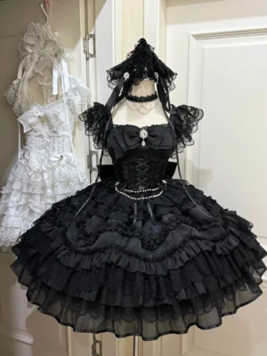 Black gothic wedding lolita JSK dress on mannequin featuring tiered ruffled tulle skirt lace trim sleeves and pearl waist chain details