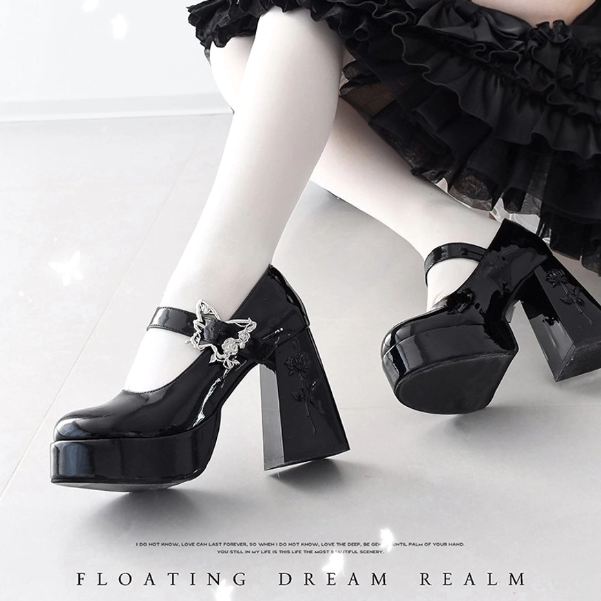 Black Mary Jane platform Lolita heels with rose-butterfly buckle worn on model's legs styled with ruffled black lolita skirt and white sheer stockings