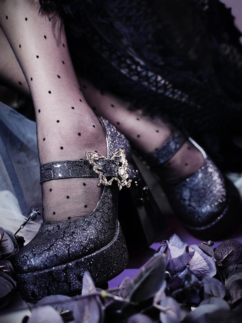 Dark glitter purple-black Mary Jane platform Lolita heels with metallic butterfly buckle and thick platform worn on model's paired feet with polka dot sheer stockings on dark floral background