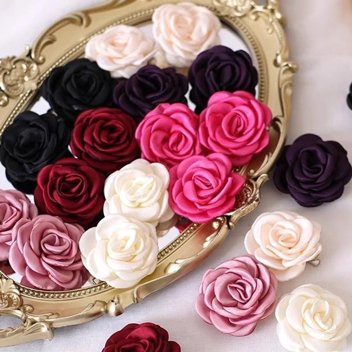 Mixed fabric rose hair accessories collection on vintage golden mirror tray displaying soft satin fabric texture and rich color palette