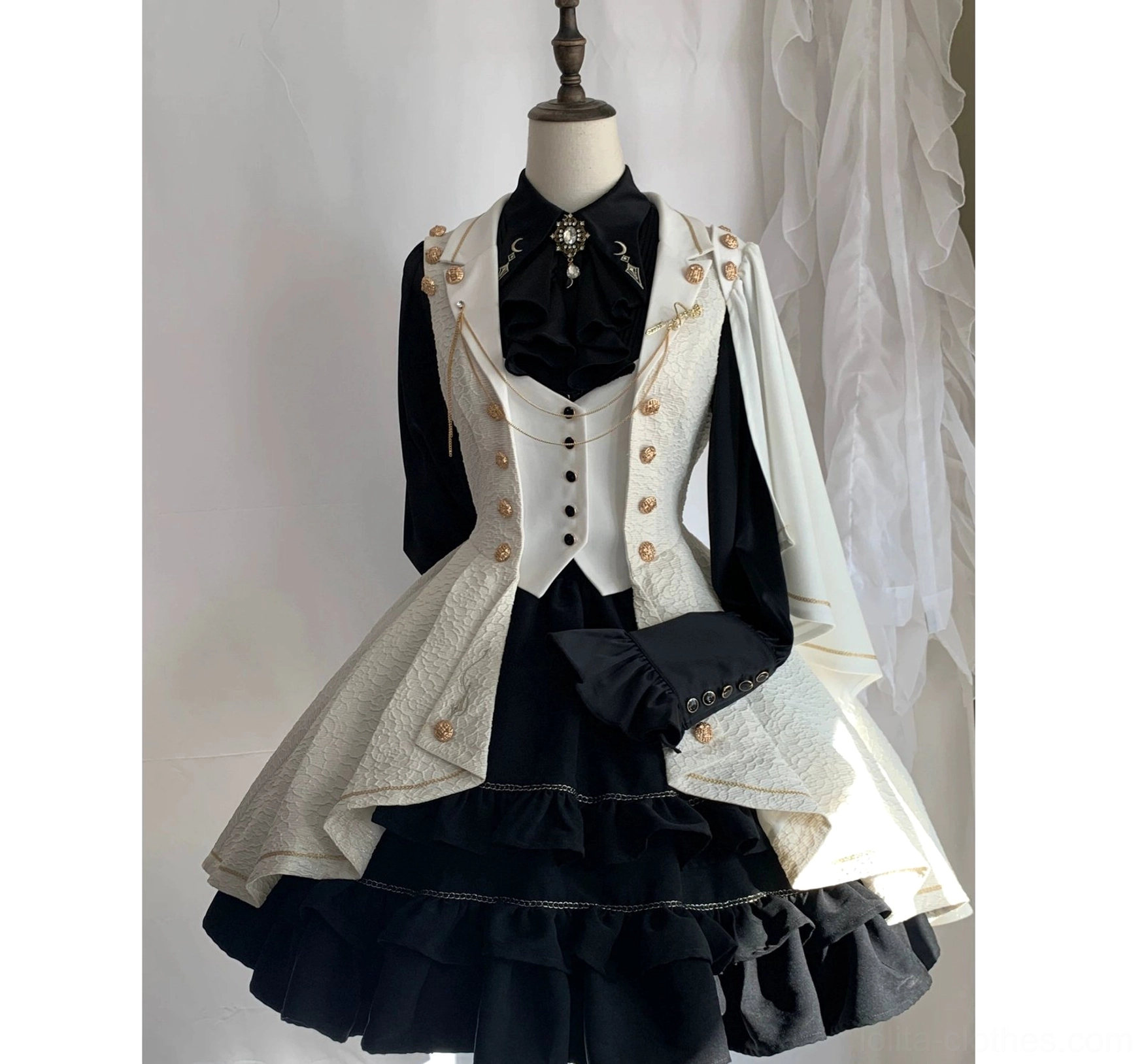 Fallen Moon Rule cream white and black military lolita dress set, frontal mannequin display with sheer curtain background, showing fitted waistcoat with gold buttons, black inner blouse, tiered ruffled black underskirt, and detachable cape sleeves