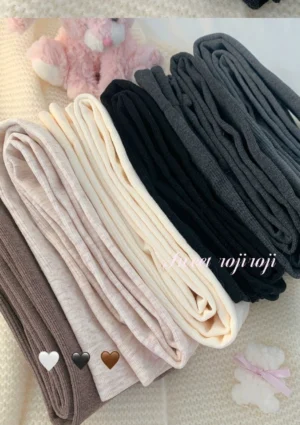 Multiple color options of thickened fleece lolita thermal pantyhose folded on plush bed with cute plush toy decoration