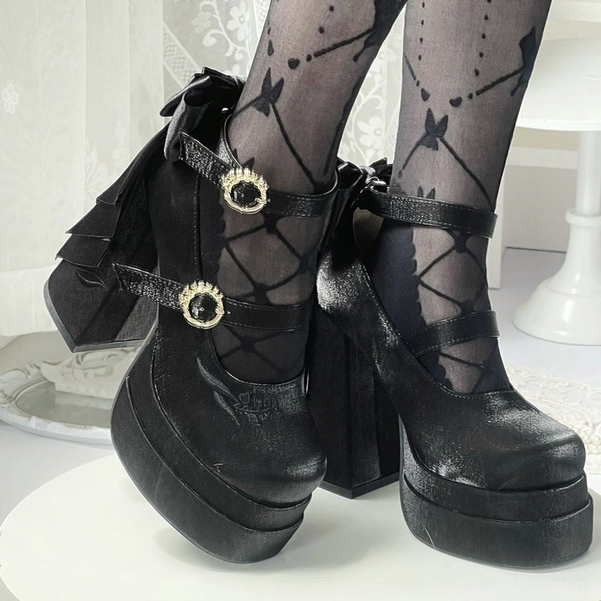 Matte black lolita platform high heels with dual decorative straps and gold round buckles, front low view paired with butterfly-patterned fishnet stockings