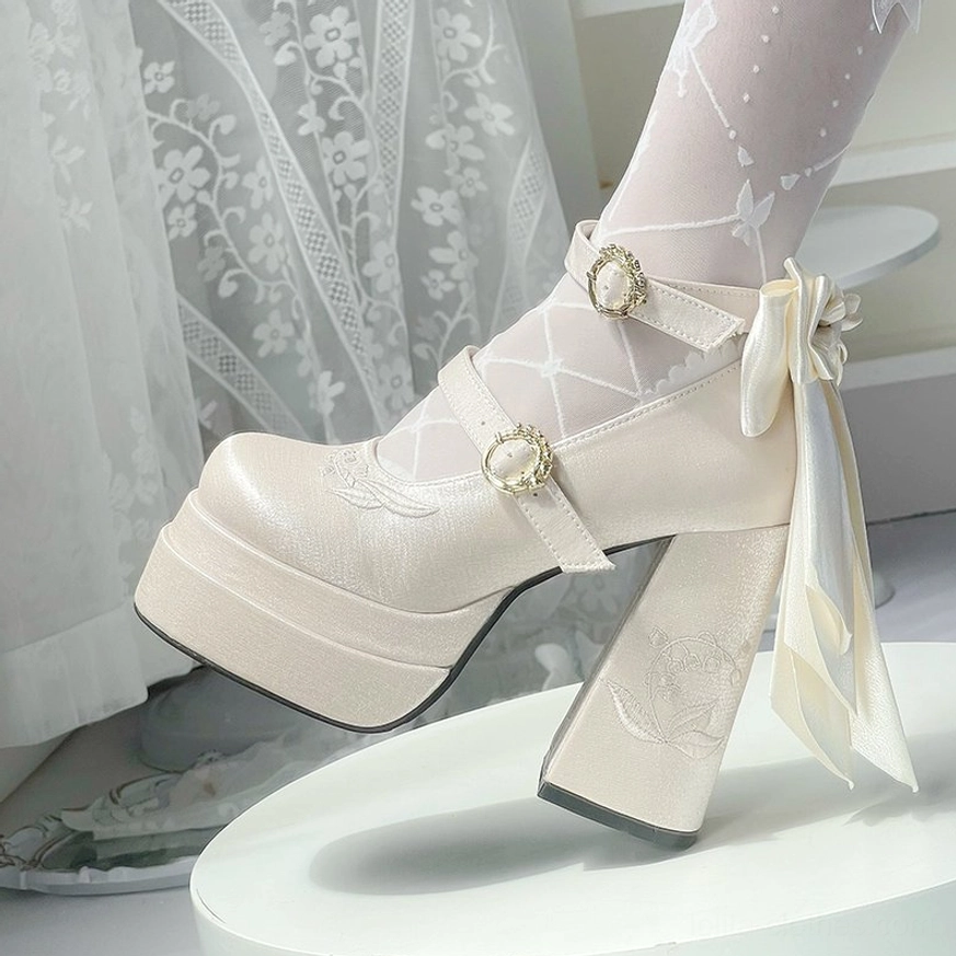 Cream beige lolita platform high heel shoes with satin back bow and round gold decorative buckles, low angled side view worn with sheer patterned thigh-high stockings