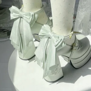 Pastel light green lolita platform high heels with layered satin back bow and embossed floral heel details, top-down close-up view of paired shoes worn with dotted beige sheer stockings