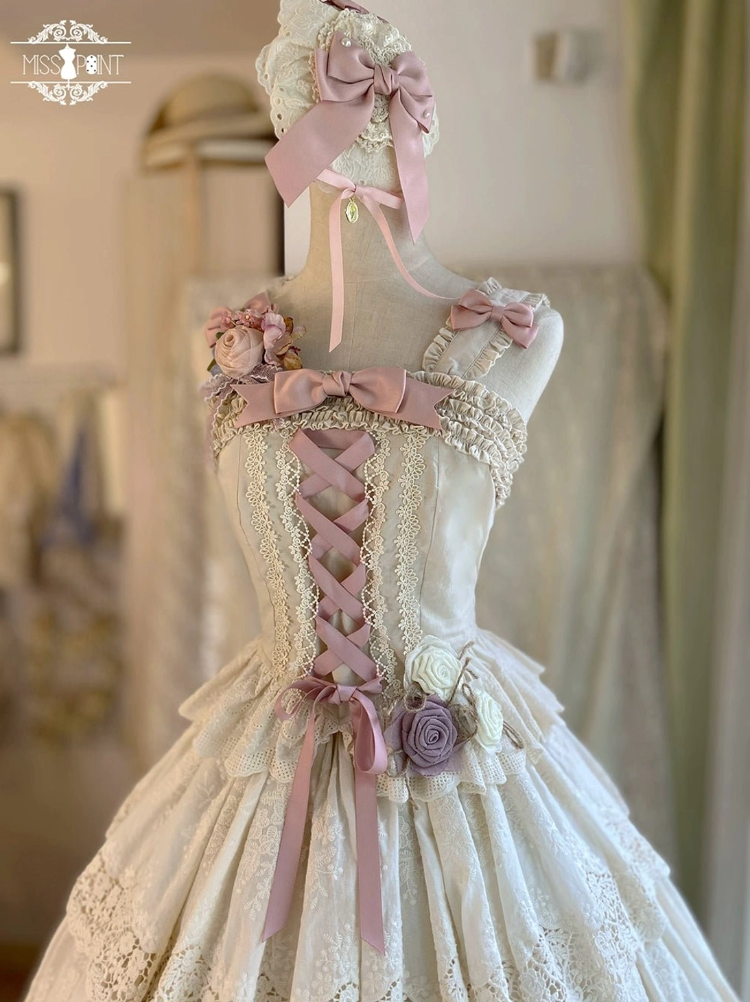 Forest Waltz ivory fitted lolita camisole with pink ribbon bow detailing, water-soluble lace front panel, and adjustable drawstring waist - front view on dress form in boutique setting
