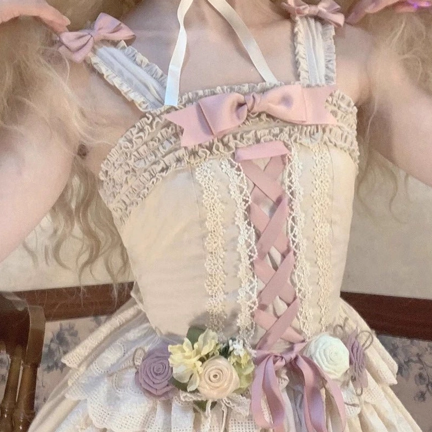 Close-up of Forest Waltz lolita camisole bodice showing pink satin shoulder bow, pink lace-up front detail, delicate lace trim, and fabric flower waist accent on model