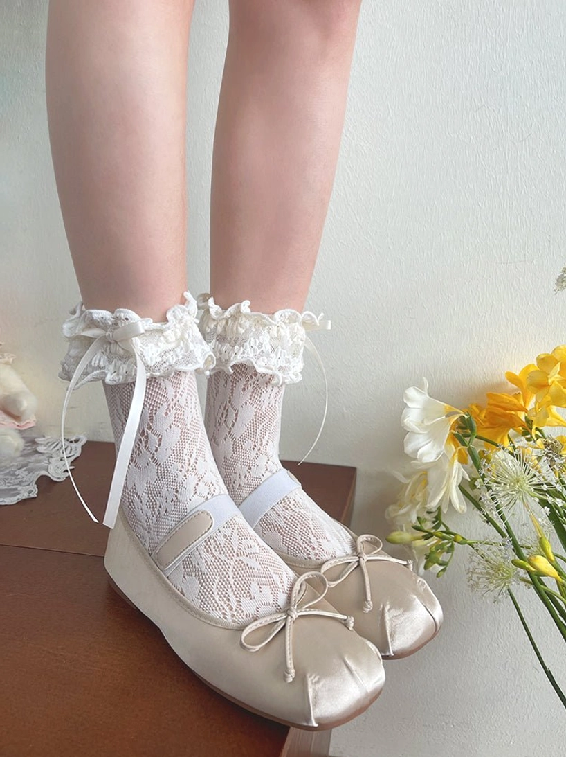 French Lolita mid-calf lace socks on-foot display with off-white floral lace, delicate ruffled cuff and satin bow, paired with beige ballet flats on white background