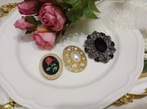 Vintage French rose Lolita brooch collection displayed on a white ceramic plate with pink roses and ornate gold tableware