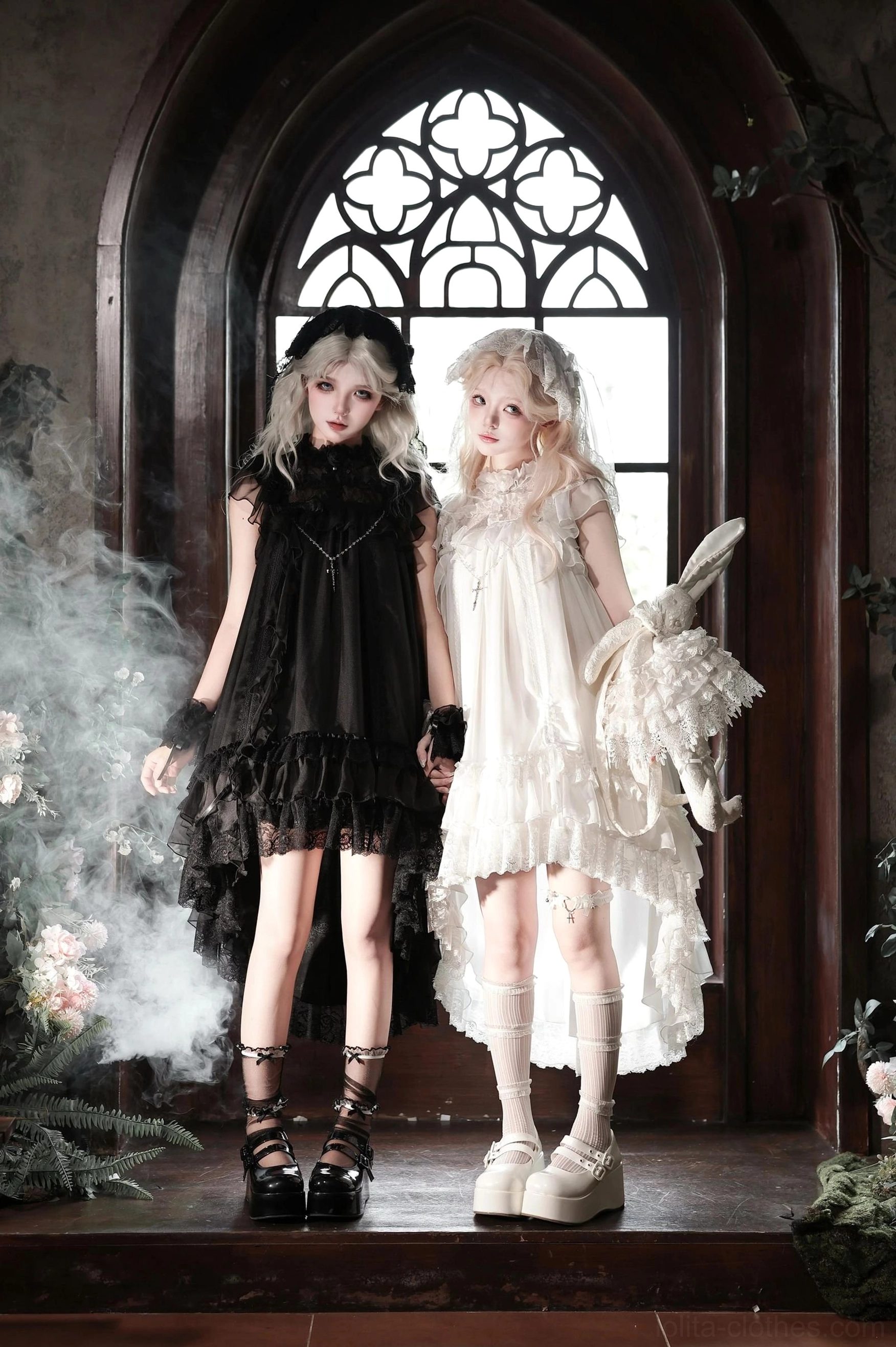 Black and white gothic lolita one-piece dresses with high-low ruffled hems featuring layered chiffon and lace details worn by models in vintage church setting