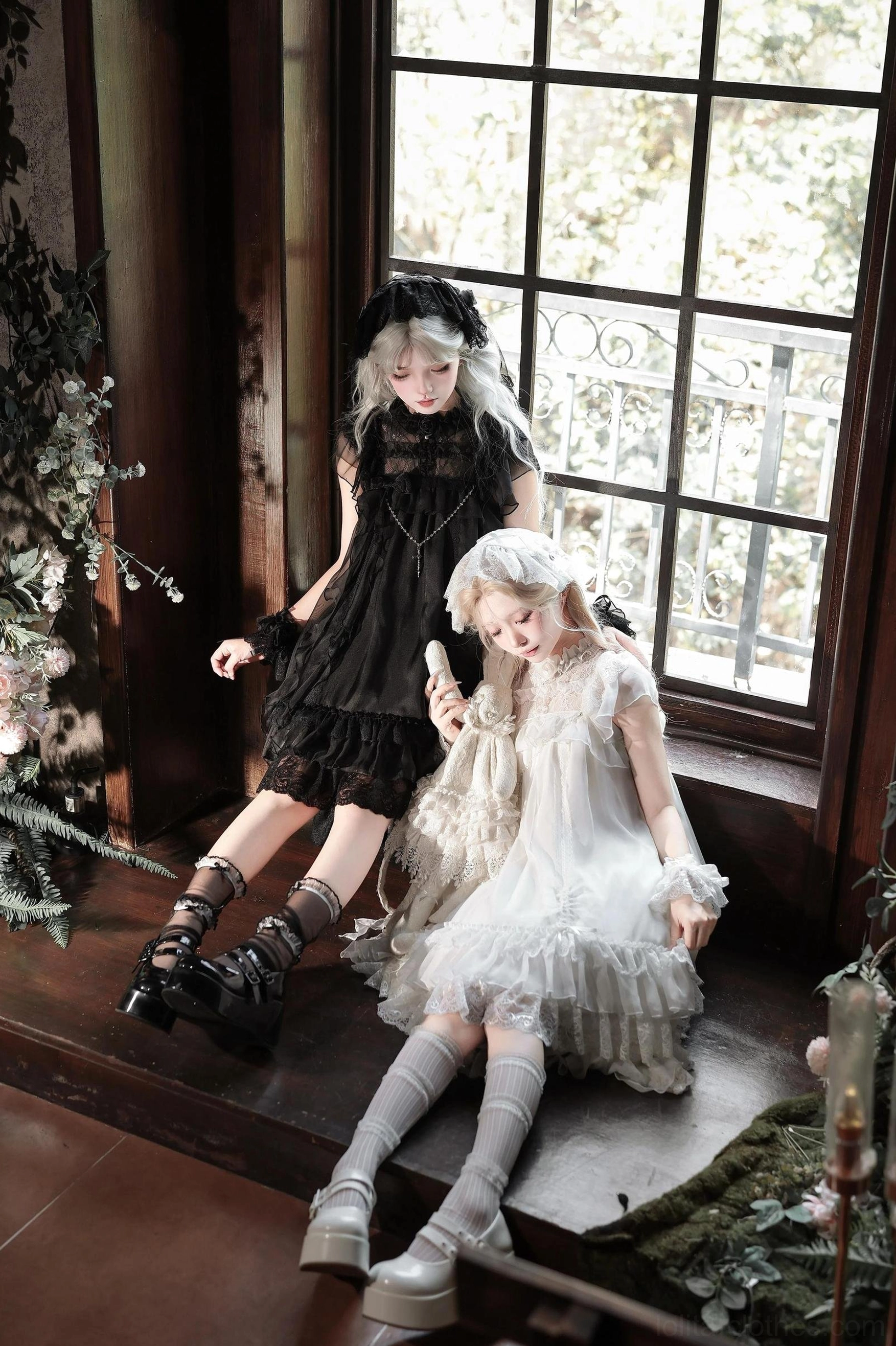 Black and white gothic lolita OP dresses featuring layered lace and tulle ruffled hems photographed in side and rear views with platform boots