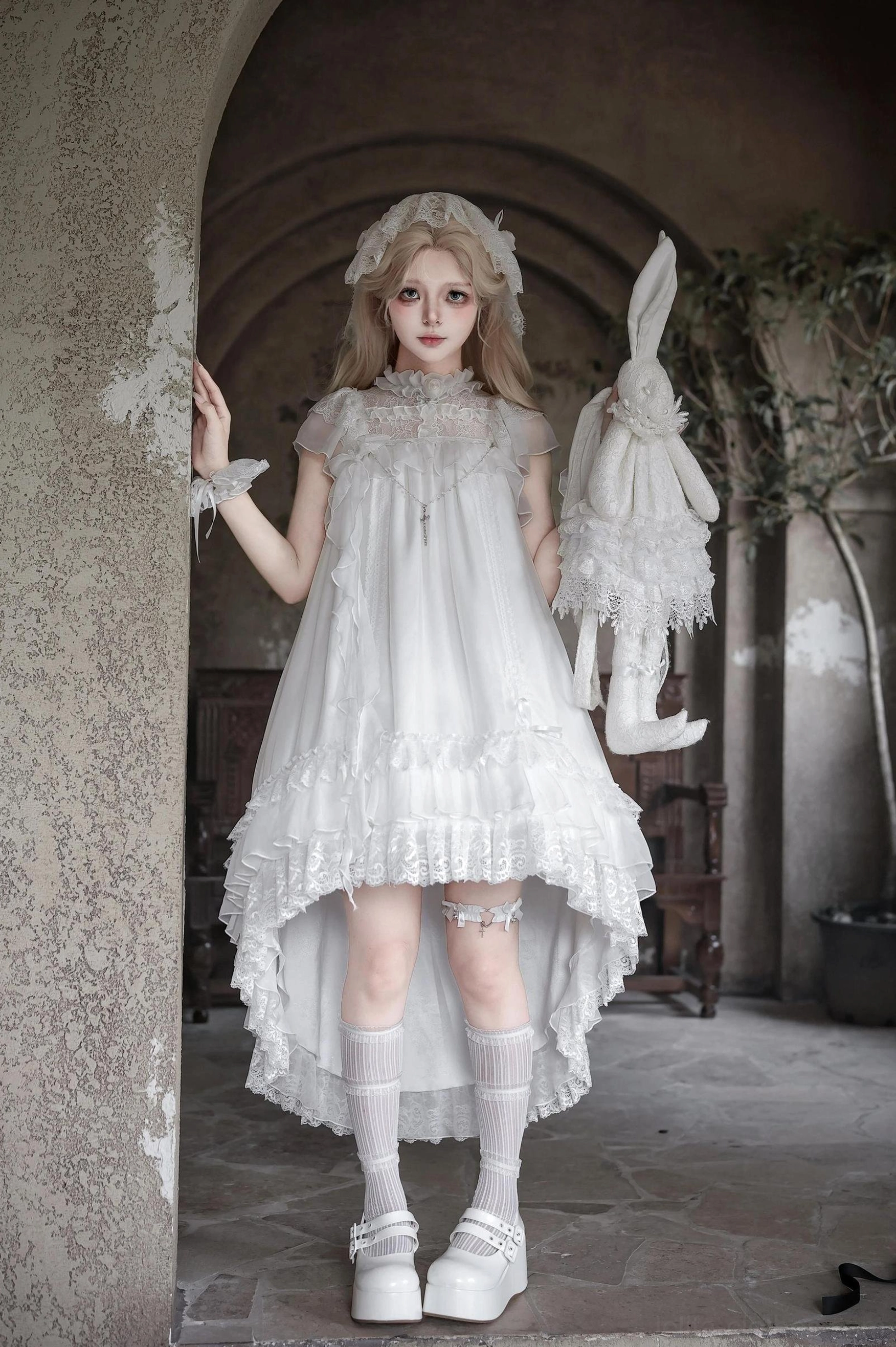 White gothic lolita OP dress with high-low hem ruffled lace trim, platform loafers, and detachable plush rabbit hand accessory