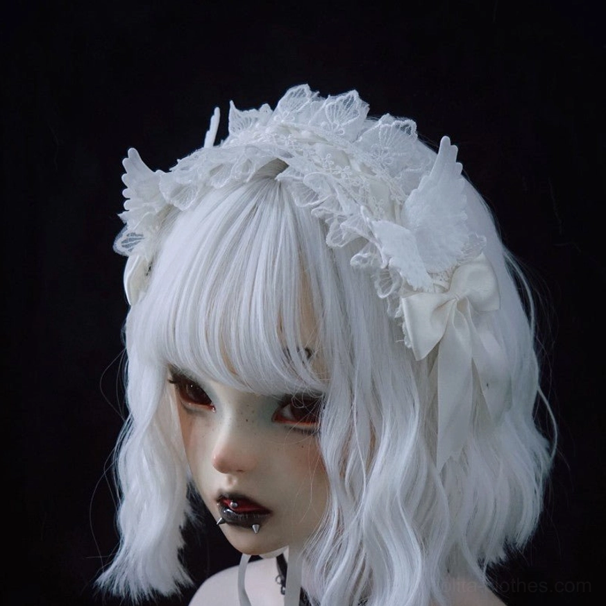 Gothic lolita white lace angel wings hairband worn on BJD bust with white bob wig, left front three-quarter view showing frilled lace details and satin bows