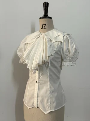 Off-white Gothic Lolita bat-collar shirt with detachable pleated jabot displayed on dress form, featuring puffed short sleeves and fitted waist silhouette