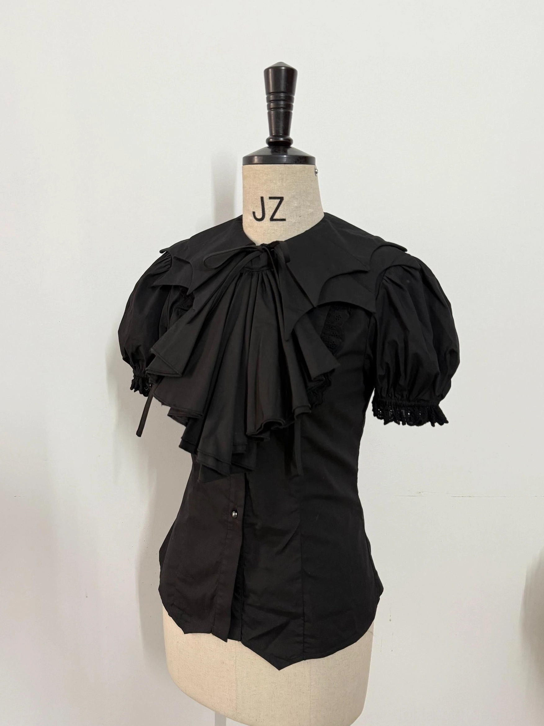 Off-white Gothic Lolita bat-collar shirt with detachable pleated jabot, puffed sleeves, and fitted silhouette on dress form