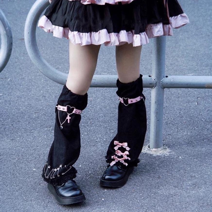 Bare leg view of gothic suede leg warmers featuring dual decorative straps ribbon lace-up lower cuffs studded edges worn with tiered black pink lolita skirt