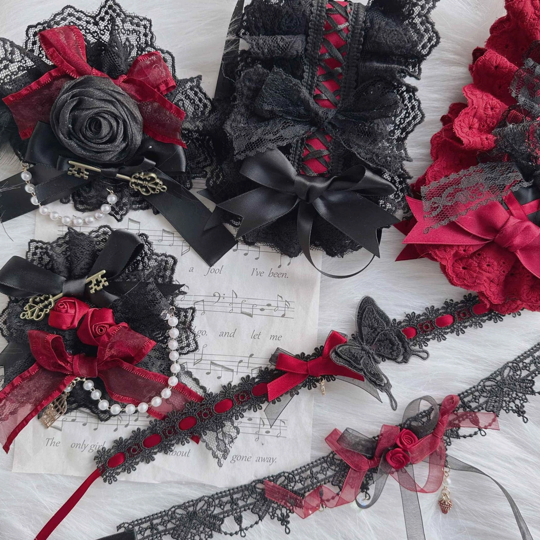 Handmade Gothic Lolita accessory collection arrangement showing complete variety of styles with black lace, red satin and decorative metal elements
